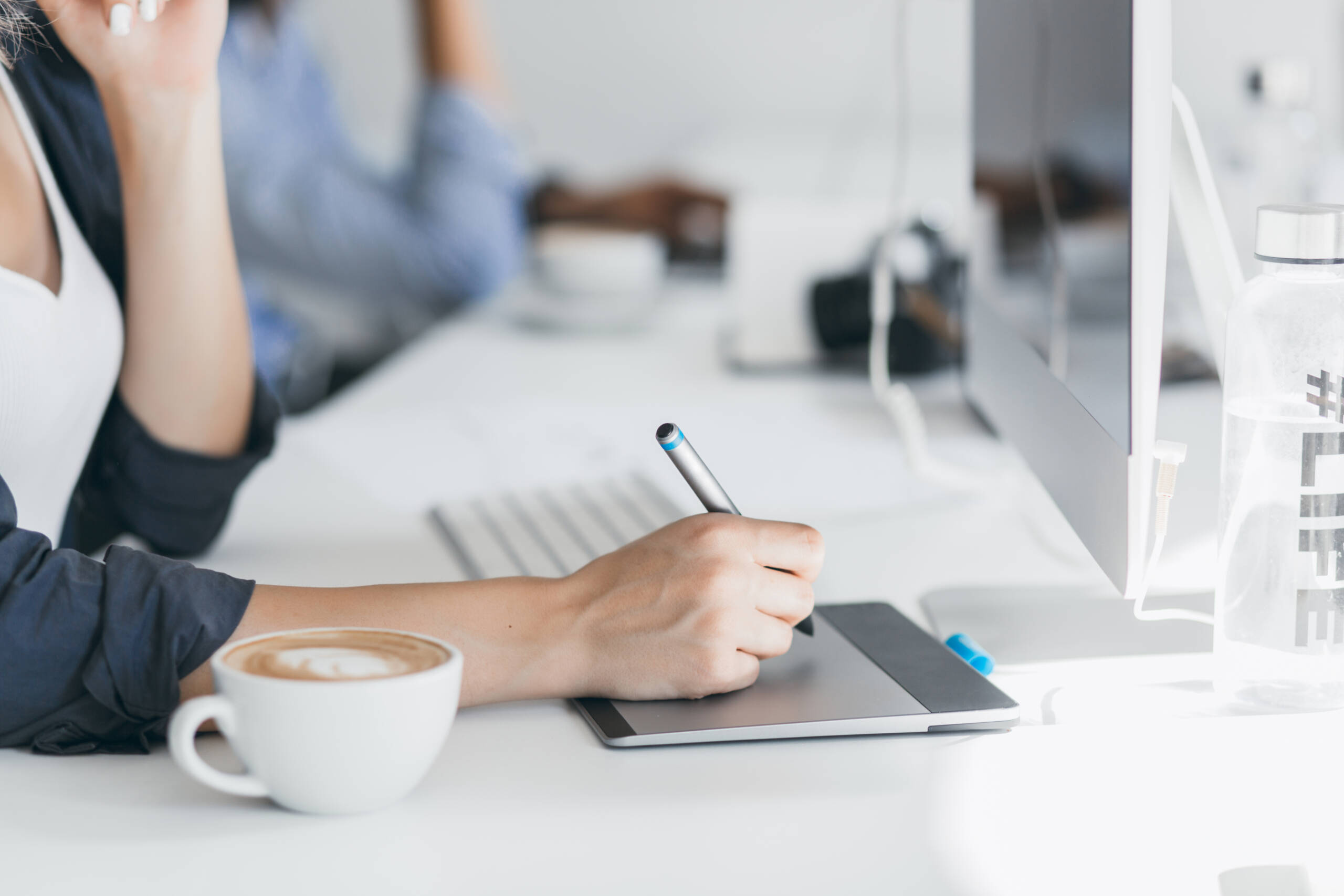 Close-up photo of female hand holding stylus on tablet. Indoor portrait of freelance web-developer working on project during coffee-break in office.. working
